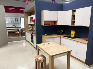 Kyiv, Ukraine - January 03, 2025: Stylish modern kitchen featuring wooden countertops, white cabinets, and a minimalist design. The display highlights functionality and aesthetic appeal, with an accompanying dining area visible in the open layout sto clipart