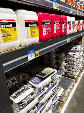 Kyiv, Ukraine - January 03, 2025: Colorful containers and cement bags are organized on shelves in a hardware store, offering a variety of materials for construction and renovation projects. clipart