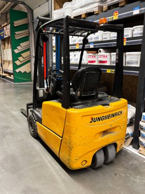 Kyiv, Ukraine - January 03, 2025: A yellow forklift is positioned in a store aisle, surrounded by shelves stocked with hardware materials and tools, typically used for lifting and moving heavy goods.  clipart