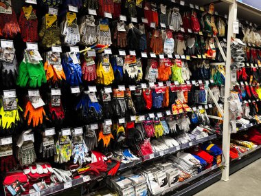 Kyiv, Ukraine - January 03, 2025: Numerous colorful hand protection gloves arranged neatly on shelves in a retail shop. Selection includes various styles and designs suitable for diverse tasks, emphasizing durability and function in both work and per clipart