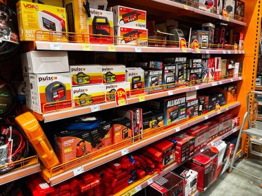 Kyiv, Ukraine - January 03, 2025: A selection of automobile battery chargers and related equipment displayed on retail store shelves. clipart