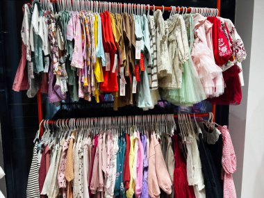 Kyiv, Ukraine - January 04, 2025: A display rack in a boutique showcasing vibrant and stylish children's clothing including dresses and tops, emphasizing variety and quality suitable for different occasions. clipart