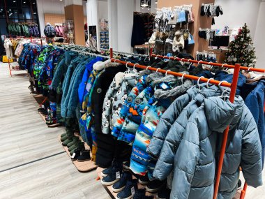 Kyiv, Ukrayna - 04 Ocak 2025: İyi aydınlatılmış bir giyim mağazası müşteriler için düzenlenen raflarda çeşitli renkli kışlık ceketler ve aksesuarlar sergilenmektedir. Arka planda şapkalar, eldivenler ve diğer önemli kış öğeleri yer alıyor..