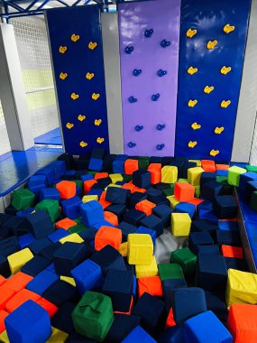 Çocuklar için mavi ve mor duvarlar ve köpük blokları içeren canlı bir tırmanış tertibatı. Eğlence ya da spor aktiviteleri için uygun bir ortam..