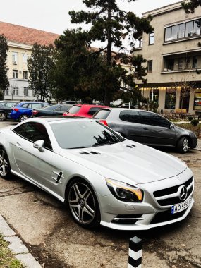 Uzhgorod, Ukrayna - 07 Ocak 2025: Pürüzsüz, lüks bir Mercedes-Benz SL 63 AMG R 231 üstü açılabilir otomobil, diğer araçlar ve binalar tarafından çevrelenmiştir. Görüntü şık bir şehir yaşam tarzını ve modern vejeteryanı kapsıyor.