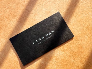 Kyiv, Ukraine - January 07, 2025: A black Zara Man card with elegant text rests on a light, textured surface, illuminated by soft sunlight creating shadows. The minimalist design emphasizes branding, sophistication, and simplicity. clipart