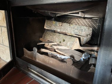 Odunların ve şöminenin içine dikkatlice istiflenmiş odunların bir fotoğrafı, yakılmaya ve ısınmaya hazır, mevsimsel ve evle ilgili senaryolar için rahatlık ve kırsal bir cazibe hissi yaratıyor..