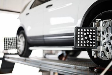 Profesyonel bir otomotiv garajında bir arabanın tekerinin düzgün bir hizalama kontrolü alırken yakın çekim görüntüsü..