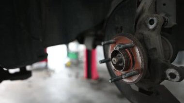 Bir arabanın bakım yapılan fren sisteminin yakın çekim görüntüleri. Video, profesyonel bir otomotiv tamirhanesinde fren diski ve çevre bileşenleri vurguluyor..
