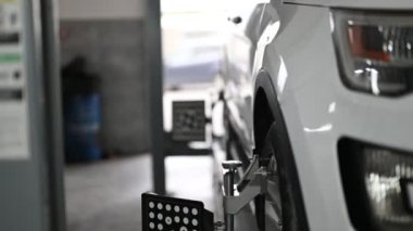 Profesyonel bir otomotiv tamirhanesinde bir aracın lastiğine tutturulmuş bir araba tekerleği hizalama makinesinin yakın çekim görüntüsü..