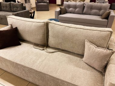 Bir sergi salonu ortamında zarif ve rahat koltukların sergilenmesi, tasarımlarının ve rahatlıklarının altını çizmek. Ayarlar, çeşitli oturma odası estetikleri için mükemmel, şık yastıklı tarafsız kumaş renkleri sergiliyor..