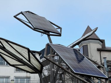 Açık bir kentsel alandaki güneş panelleri, açık gökyüzü ile çağdaş yapıların arasında sürdürülebilir teknoloji sergiliyor..