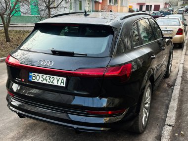 Kyiv, Ukrayna - 30 Ocak 2025: Modern siyah Audi E-tron S kentsel konut binalarının yakınındaki bir caddeye park edilmiştir. Sahne, şehir ortamında çağdaş bir otomobilin tasarım ve tarzını gösteren araçları ve kentsel çevreyi gösteriyor.