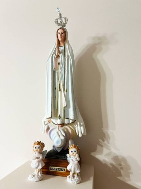 Sculpture of Our Lady of Fatima on a pedestal surrounded by angel figures conveying serenity. clipart