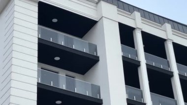 Camdan balkonları, beyaz ve siyah cepheleri olan modern bir apartman. Şık mimari ve kentsel yaşam konsepti.