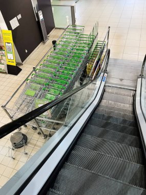 Kyiv, Ukrayna - Şubat 04, 2025: Aydınlık bir mağaza ortamında yürüyen merdiven yakınındaki alışveriş arabaları