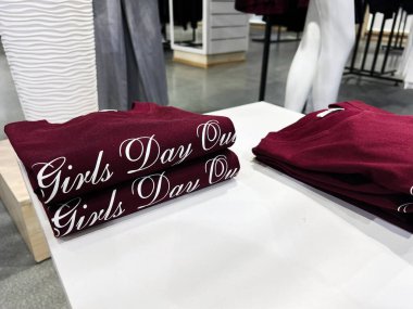 Kyiv, Ukrayna - 05 Şubat 2025: Kızlar Günü yazılı katlanmış Burgundy tişörtleri bir mağaza tezgahında sergilendi