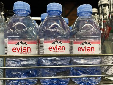 Kyiv, Ukrayna - 4 Şubat 2025: Temiz etiket ve kapaklarla düzgünce düzenlenmiş üç Evian maden suyu şişesi