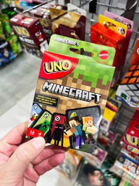 Kyiv, Ukraine - February 09, 2025: Minecraft themed Uno card game package held in hand and displayed in a retail store. clipart