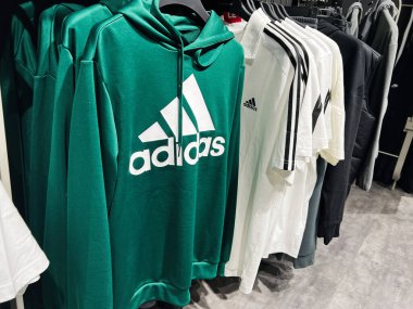 Kyiv, Ukraine - February 09, 2025: Adidas hoodies and T-shirts neatly displayed on hangers in a retail clothing store clipart