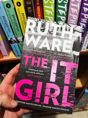 Kyiv, Ukraine - February 09, 2025: A hand holding a book titled The It Girl by Ruth Ware in a bookstore aisle. clipart