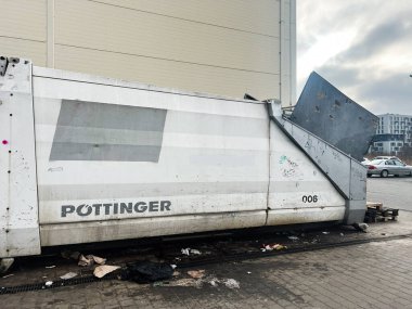 Lviv, Ukrayna - 12 Şubat 2025: Pottinger beyaz endüstriyel konteynırı çevresindeki çöp yığınları ve park halindeki araçlarla dışarı yerleştirildi