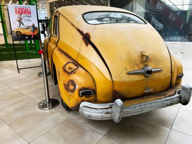 Lviv, Ukrayna - 12 Şubat 2025: Paslı, eski, sarı GAZ-M20 Pobeda arabası sergilenen döşeme döşeme döşeme üzerinde, yanındaki poster eşliğinde