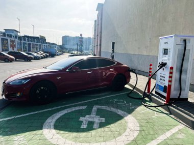 Lviv, Ukrayna - 12 Şubat 2025: Kırmızı bir Tesla Model S elektrikli araç kamu elektrik istasyonunda park edilmiş ve şarj ediliyor