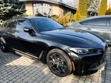 Lviv, Ukrayna - 12 Şubat 2025: Lüks siyah BMW i4 arabası güneşli bir günde banliyöde park edilmiş 