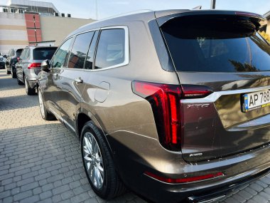 Lviv, Ukraine - February 12, 2025: Luxurious Cadillac XT6 SUV parked in a paved outdoor area, featuring sleek styling and design. clipart