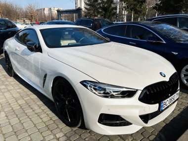 Lviv, Ukrayna - 12 Şubat 2025: Beyaz lüks BMW M850i coupe açık havada park edilmiş zarif bir tasarım.