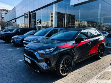 Lviv, Ukraine - February 12, 2025: Multiple Toyota vehicles displayed outside an automotive dealership under clear blue skies clipart