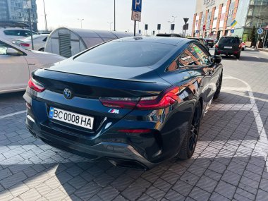 Lviv, Ukrayna - 12 Şubat 2025: Lüks BMW 8 Serisi araba sergi tarzı ve modern tasarımı ticari bir binanın önünde park etti