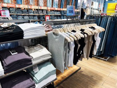 Lviv, Ukrayna - 13 Şubat 2025: Moda mağazasının iç dekorasyonu katlanmış gömlekler, kolsuz bluzlar ve organize kot pantolon bölümü.