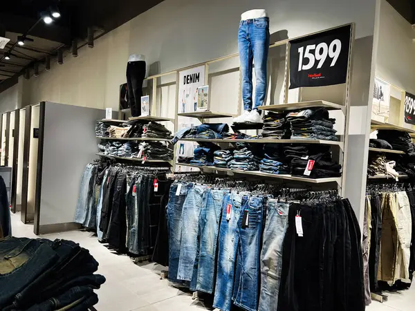 Lviv, Ukrayna - 13 Şubat 2025: Şık bir mağazada raflarda ve raflarda düzenlenmiş bir kot pantolon perakendecisi.