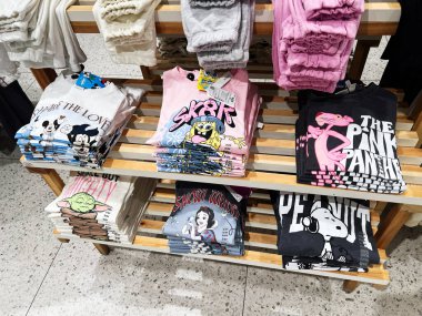 Lviv, Ukrayna - 13 Şubat 2025: Bir perakende mağazasındaki ahşap raflarda özenle sergilenen çeşitli karakter temalı tişörtler.