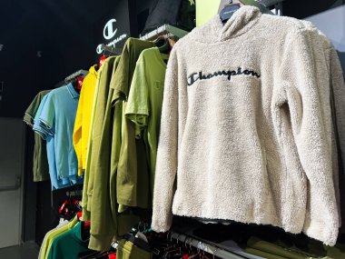 Lviv, Ukrayna - 16 Şubat 2025: Kapüşonlu yün kazak ve canlı gömlekler modern bir perakende mağazasında sergileniyor