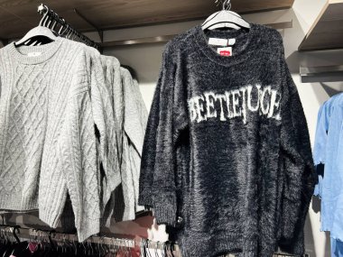 Lviv, Ukrayna - 16 Şubat 2025: Çağdaş Beetlejuice örgü ve grafik kazakları iyi düzenlenmiş bir gardırop ortamında sergilendi