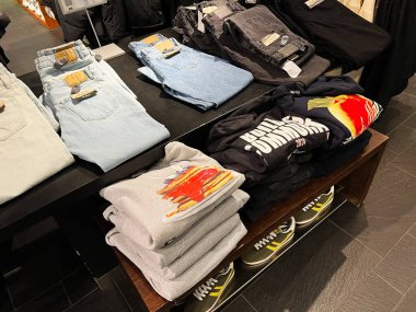 Lviv, Ukrayna - 16 Şubat 2025: Şık katlanmış kot ve baskılı sweatshirt 'lerin yer aldığı bir perakende masasında giysiler düzenlendi