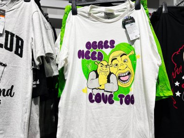 Lviv, Ukrayna - 16 Şubat 2025: Devlerin de sevgiye ihtiyacı var. Giysi perakende ortamında sergilenen tişörtlerde Shrek tasarım ve sloganları yer aldı