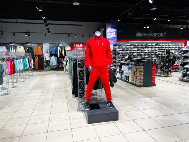 Lviv, Ukrayna - 16 Şubat 2025: Parlak bir iç mekanda moda giysiler, spor ayakkabıları ve satış tabelaları sergileniyor