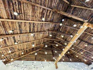 Kırsal ahşap kirişler narin sicim ışıklarıyla aydınlatılarak rahat bir ortam yaratıyor.