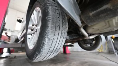 Araba tamircisi tamircide araba kaldırma lastiği değiştiriyor. Arka planda tamirci olan lastiğin kapanışı.