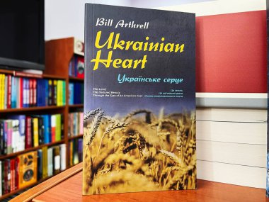 Lviv, Ukraine - February 20, 2025: Ukrainian heart by Bill Arthrell. A book with wheat cover theme, located in a colorful and organized library clipart