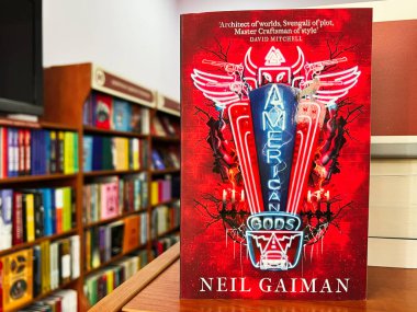 Lviv, Ukraine - February 20, 2025: American Gods by Neil Gaiman. Decorative book cover displayed in a bookstore emphasizing books and literature clipart