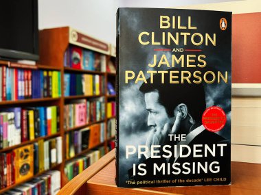 Lviv, Ukraine - February 20, 2025: President Is Missing by Bill Clinton and James Patterson. Close-up of a thriller book cover showcased in a colorful bookstore setting. clipart