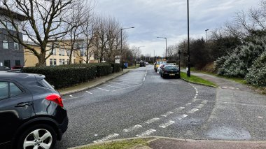 Londra, İngiltere - 21 Şubat 2025: Enfield, Londra 'da şehir caddesi park halindeki arabalarla ve bulutlu hava koşullarıyla.