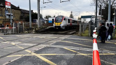 Londra, İngiltere - 21 Şubat 2025: Enfield, Londra, İngiltere 'de yayalar ve kentsel çevre ile tren geçişi