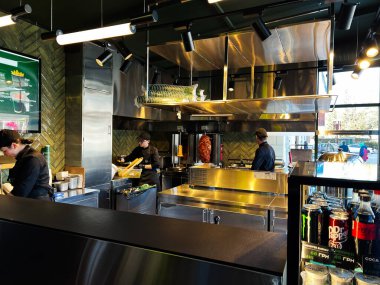 Kyiv, Ukrayna - 16 Şubat 2025: Çağdaş dekor ve aletlerin yer aldığı iyi donanımlı bir shawarma restoranında aşçılar.