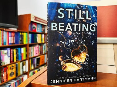 Lviv, Ukraine - February 20, 2025: Book titled Still Beating by Jennifer Hartmann in a bookstore shelf surrounded by other books. clipart